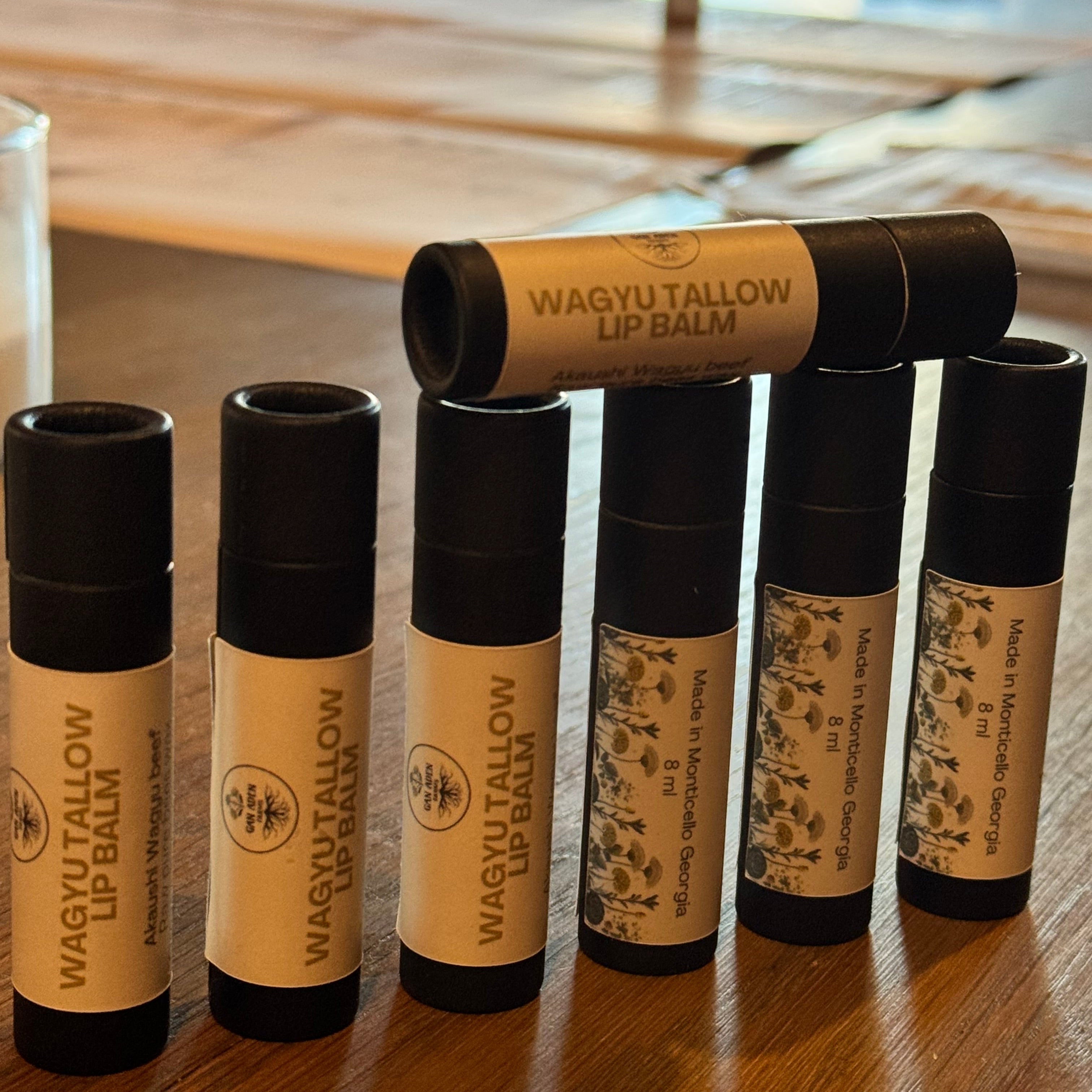 Row of Wagy Tallow lip balms on a wooden surface