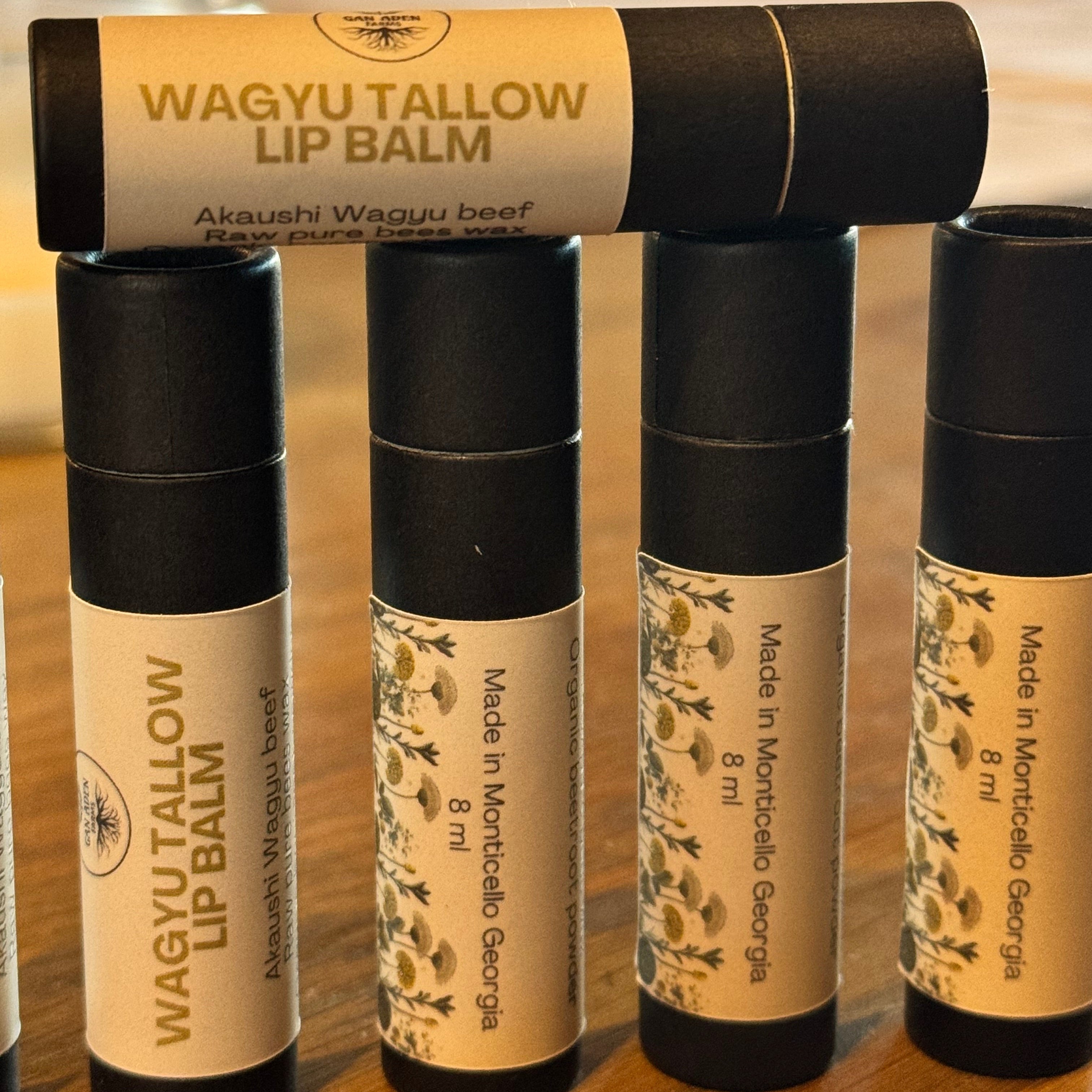 Stack of Wagyu Tallow lip balm tubes on a wooden surface