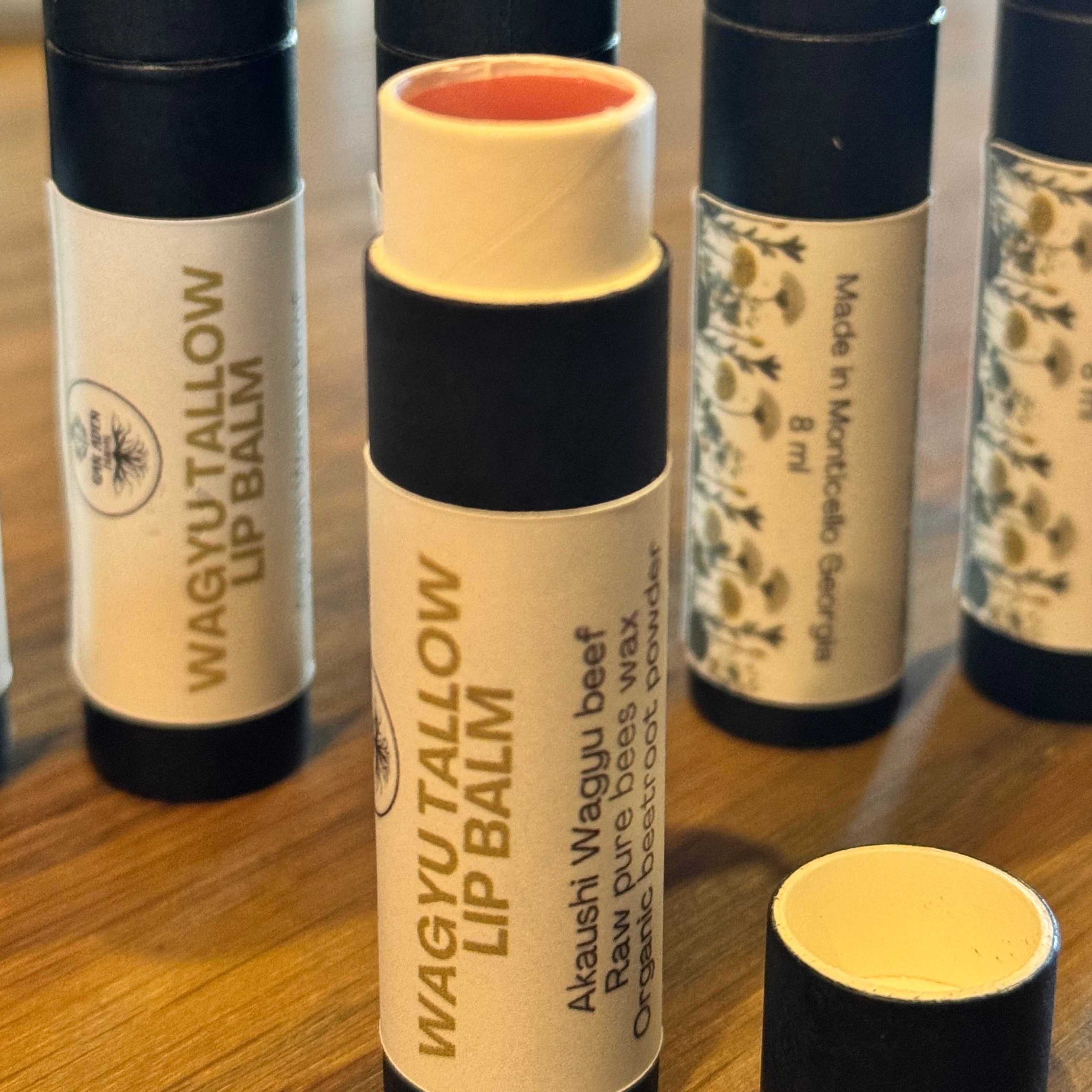 Lip balm tubes with visible branding on a reflective surface