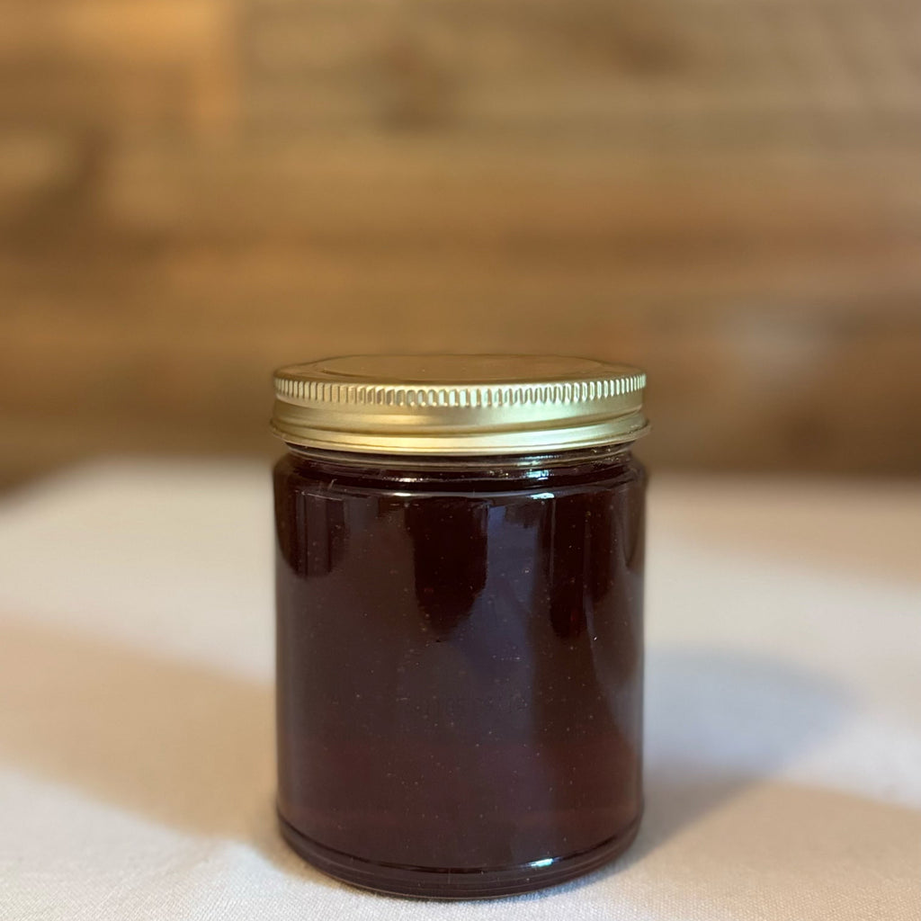 Amber glass jar with a gold lid on a white surface with a wooden background