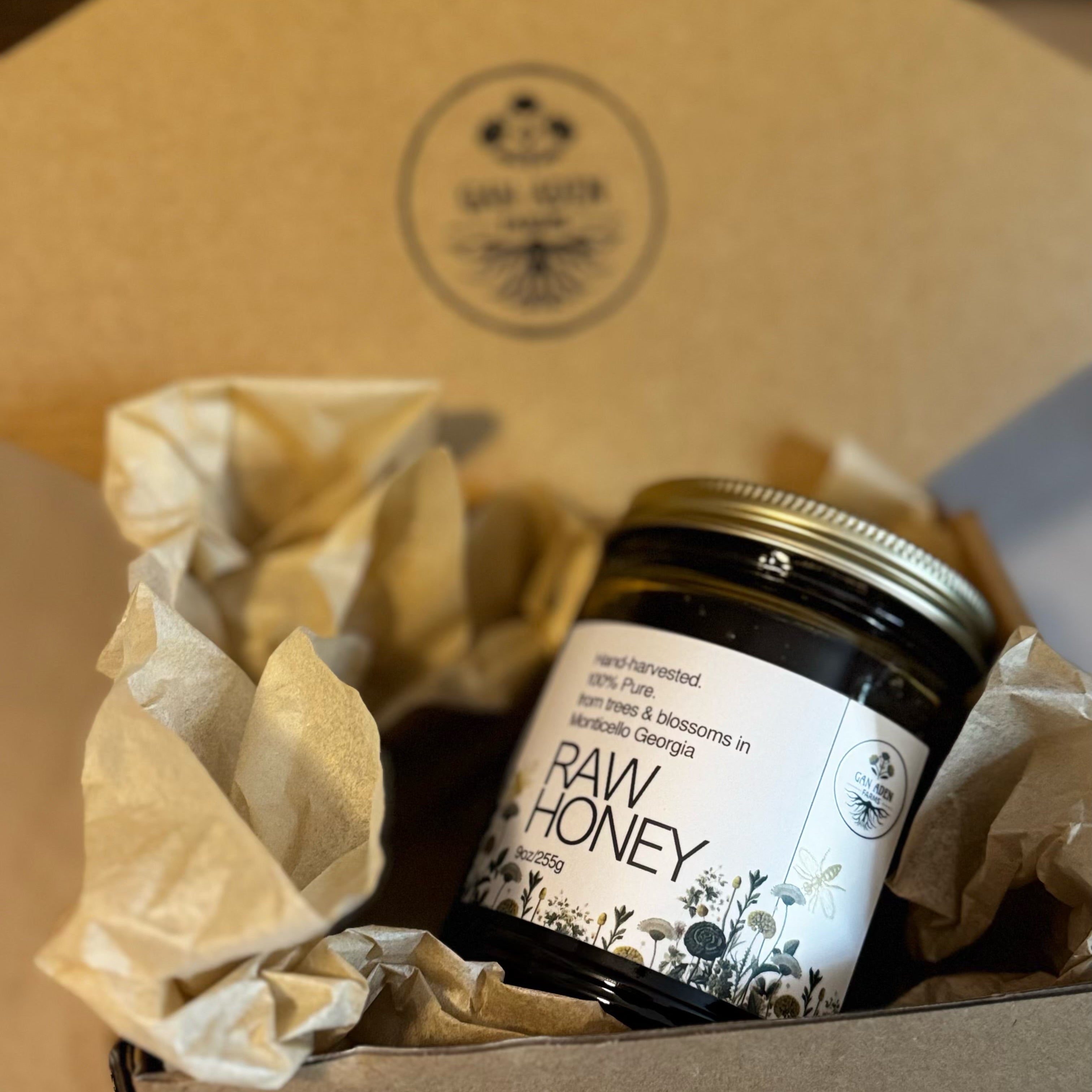 Jar of raw honey in a box with a visible brand logo.